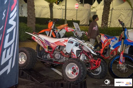 A white and red Yamaha quad displayed among motorcycles at Bagatelle Motor Festival, photographed at night.
