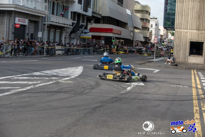 Karts passing spectators and everyday buildings in Port Louis.