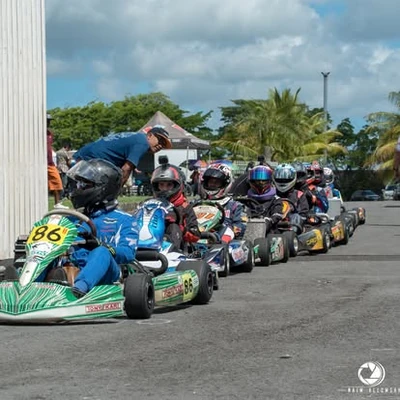 Helmeted kart drivers waiting in the paddock, with kart 86 nearest the camera.